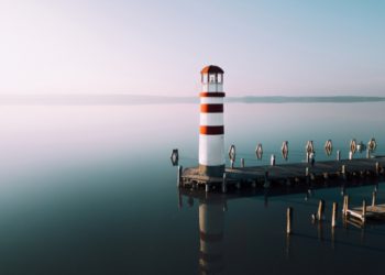Lighthouse on pier surrounded by water birthday card